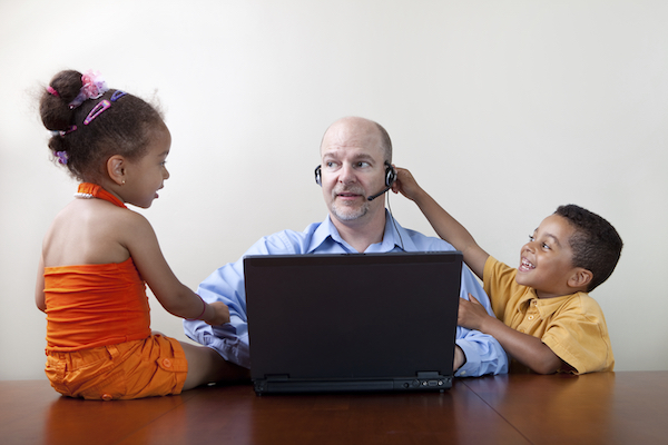 Two children bothering their father as he works on the computer
