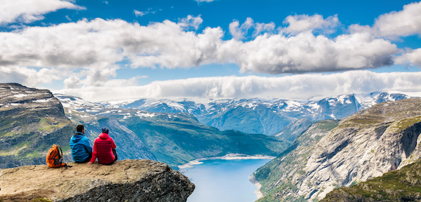 Two people sitting on the edge of a cliff as they look at the beautiful view