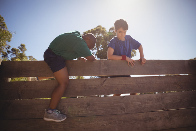 Photo of two kids climbing a wooden wall