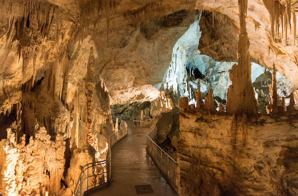 The walls and caverns of a cave surrounding a man made walkway