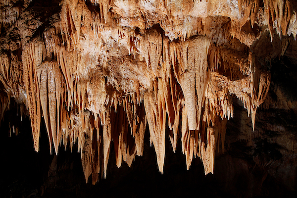 Sharp icicle like formations on the ceiling of a cave